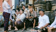 Sebuah keluarga sedang melihat brosur destinasi wisata dengan ekspresi mempertimbangkan, di hadapan mereka terpampang daftar harga tiket masuk ke berbagai objek wisata populer yang terus meningkat. Gambar ini merefleksikan dilema banyak wisatawan dalam merencanakan liburan dengan anggaran terbatas.