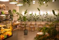 Sebuah kafe modern dengan jendela besar menghadap pemandangan pegunungan hijau yang asri di Sentul, menciptakan suasana tenang dan estetik untuk menikmati secangkir kopi hangat. Interior kafe didominasi material kayu dan pencahayaan hangat, mengundang pengunjung untuk bersantai dan melepaskan penat.