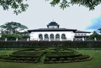 Sebuah keluarga sedang berdiskusi sambil memegang peta dan ponsel, menggambarkan dilema perencanaan anggaran liburan di tengah kenaikan harga tiket wisata. Pemandangan ini merefleksikan tantangan yang dihadapi banyak orang untuk tetap menikmati perjalanan tanpa menguras dompet.