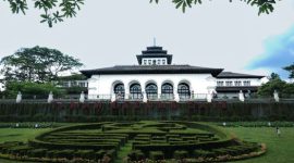 Sebuah keluarga sedang berdiskusi sambil memegang peta dan ponsel, menggambarkan dilema perencanaan anggaran liburan di tengah kenaikan harga tiket wisata. Pemandangan ini merefleksikan tantangan yang dihadapi banyak orang untuk tetap menikmati perjalanan tanpa menguras dompet.