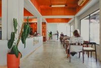 Sebuah kafe modern dengan dominasi kaca di Sentul, dikelilingi oleh pepohonan rindang dan menawarkan pemandangan alam yang menenangkan, menjadi tempat ideal untuk menikmati kopi di tengah hijaunya perbukitan.