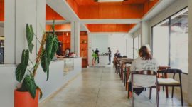 Sebuah kafe modern dengan dominasi kaca di Sentul, dikelilingi oleh pepohonan rindang dan menawarkan pemandangan alam yang menenangkan, menjadi tempat ideal untuk menikmati kopi di tengah hijaunya perbukitan.