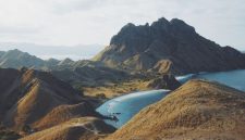Keluarga sedang menikmati keindahan padang savana di Sumba dengan latar belakang bukit-bukit hijau, menunjukkan momen kebersamaan yang tak terlupakan di tengah alam bebas. Pemandangan ini merepresentasikan keunikan destinasi liburan keluarga di Nusa Tenggara yang kaya akan petualangan dan keindahan alam.