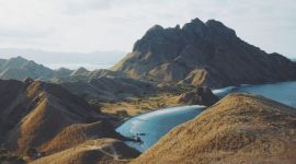 Keluarga sedang menikmati keindahan padang savana di Sumba dengan latar belakang bukit-bukit hijau, menunjukkan momen kebersamaan yang tak terlupakan di tengah alam bebas. Pemandangan ini merepresentasikan keunikan destinasi liburan keluarga di Nusa Tenggara yang kaya akan petualangan dan keindahan alam.