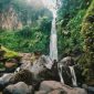 Seorang wisatawan tengah menikmati keindahan Curug Cilember, salah satu air terjun bertingkat di Bogor, dengan latar belakang hutan tropis yang rimbun dan asri. Suasana tenang di tengah gemericik air memberikan pengalaman relaksasi yang mendalam.