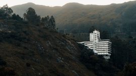 Pemandangan hotel modern dengan kolam renang yang dikelilingi pepohonan hijau rindang di kawasan Puncak, Bogor. Suasana tenang ini cocok untuk relaksasi dan melarikan diri dari hiruk pikuk perkotaan.