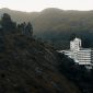 Pemandangan hotel modern dengan kolam renang yang dikelilingi pepohonan hijau rindang di kawasan Puncak, Bogor. Suasana tenang ini cocok untuk relaksasi dan melarikan diri dari hiruk pikuk perkotaan.