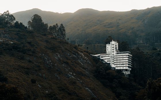 Pemandangan hotel modern dengan kolam renang yang dikelilingi pepohonan hijau rindang di kawasan Puncak, Bogor. Suasana tenang ini cocok untuk relaksasi dan melarikan diri dari hiruk pikuk perkotaan.